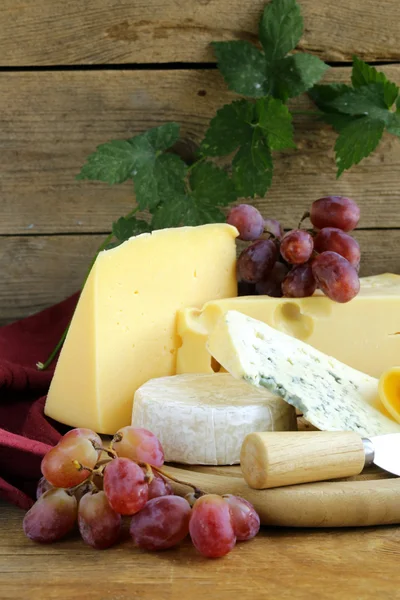 Сырная доска (Maasdam, Roquefort, Camembert) и виноград на десерт — стоковое фото