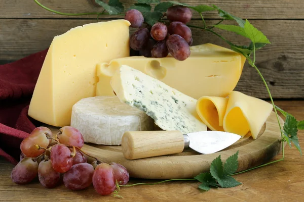 Cheeseboard (Maasdam, Roquefort, Camembert) and grapes for dessert — Stock Photo, Image