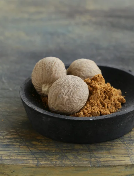 Nutmeg whole and grated on a wooden table — Stock Photo, Image