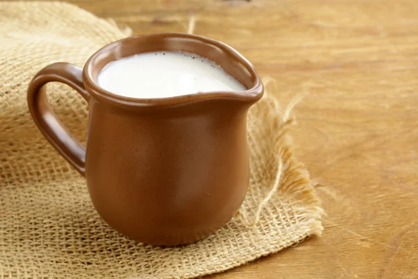 Keramická hnědá džbán plný mléka, rustikální styl — Stock fotografie
