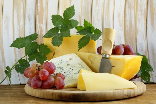 Cheeseboard (Maasdam, Roquefort, Camembert) and grapes for dessert — Stock Photo, Image