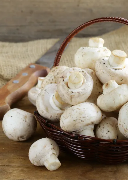 Champiñones orgánicos (champiñones) en una canasta sobre un fondo de madera — Foto de Stock