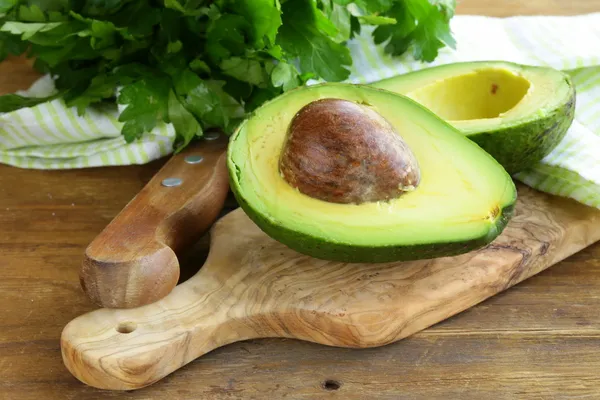 Aguacate maduro cortado por la mitad sobre una mesa de madera — Foto de Stock