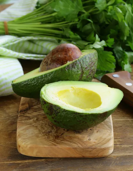 Ripe avocado cut in half on a wooden table — Stock Photo, Image