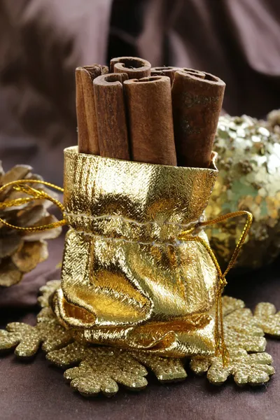 Αρωματικά ξυλάκια κανέλας σε χρυσό χριστουγεννιάτικα διακοσμητικά παιχνίδια — Φωτογραφία Αρχείου