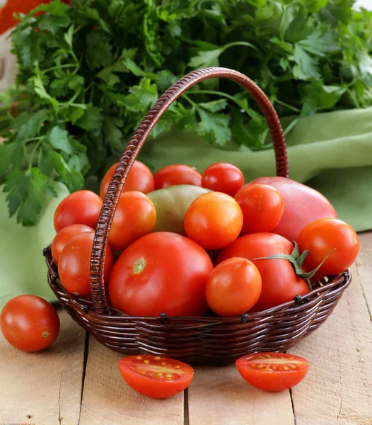 Panier avec différents types de tomates sur table en bois — Photo