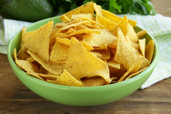 Corn chips (nachos) in a green bowl on wooden table — Stock Photo, Image