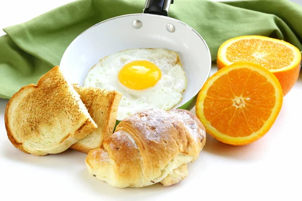 Pequeno-almoço continental - croissant, ovo frito, torradas e laranjas — Fotografia de Stock