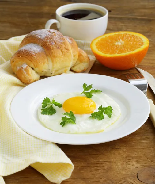 Kontinental frukost - croissant, stekt ägg, rostat bröd och apelsiner — Stockfoto