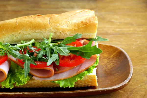 Baguette sandwich with arugula, ham and tomatoes — Stock Photo, Image