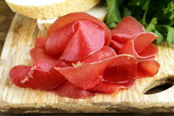 Bresaola de carne fumada em uma tábua de corte — Fotografia de Stock