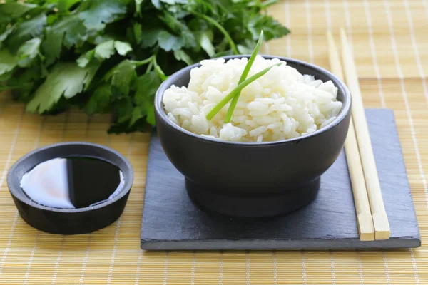 Arroz branco cozido em uma tigela preta, estilo asiático — Fotografia de Stock