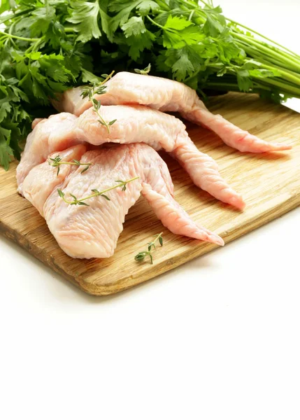 Asas de frango cru em tábua de cortar com ervas — Fotografia de Stock