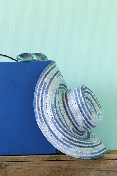 Gamla gammaldags blå resväska för resor och stranden hatt på en turkos bakgrund — Stockfoto