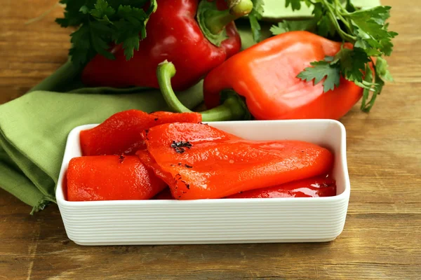 Gegrillte rote Paprika in einer weißen Schüssel auf einem Holztisch — Stockfoto