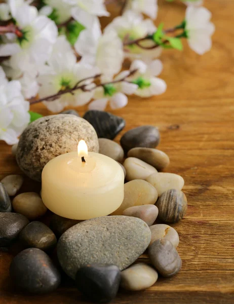 Bodegón una vela encendida y piedras sobre fondo de madera — Foto de Stock