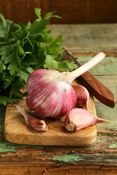 Whole garlic bulbs and segments on a cutting board — Stock Photo, Image