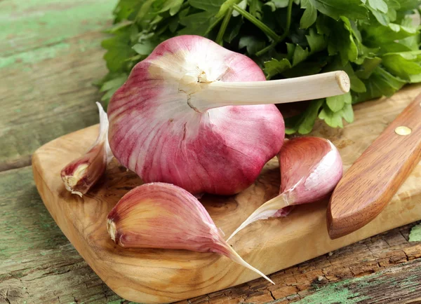 Whole garlic bulbs and segments on a cutting board — Stock Photo, Image