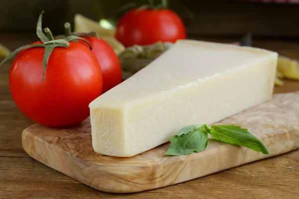 Pedazo de queso parmesano natural en una tabla de madera —  Fotos de Stock