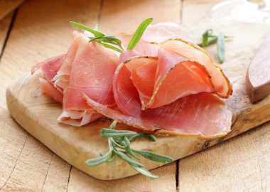 Parma jambonu (jamon) ahşap bir tahta üzerine dilimlenmiş