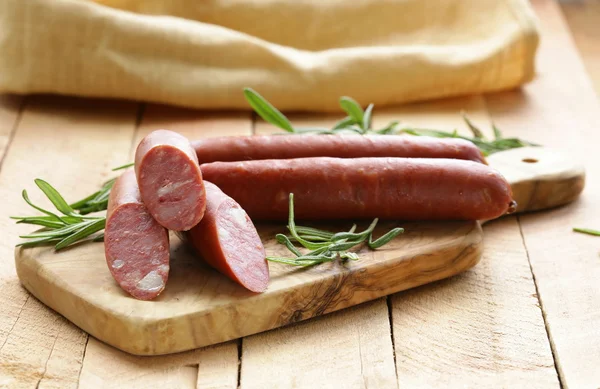 Salsiccia secca con rosmarino fresco su fondo di legno — Foto Stock