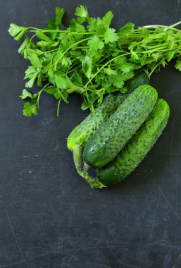 bir demet maydanoz siyah ahşap zemin ile yeşil salatalık