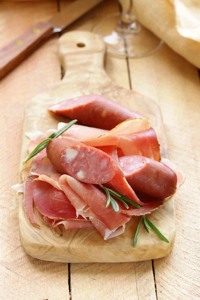 Salsiccia secca con rosmarino fresco su fondo di legno — Foto Stock