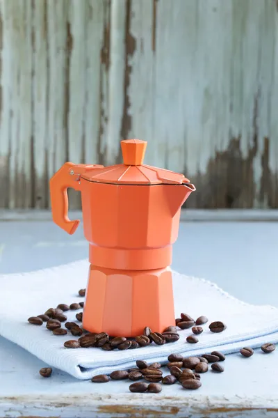 Orange metal сoffee maker and beans on blue background — Stock Photo, Image