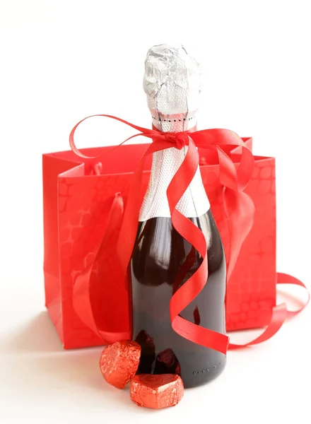 Şenlikli şişe şampanya ile çikolata ve beyaz zemin üzerine hediyeler — Stok fotoğraf