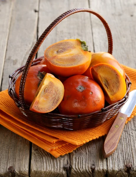 Persimmon fruits entiers et tranchés sur une table en bois — Photo