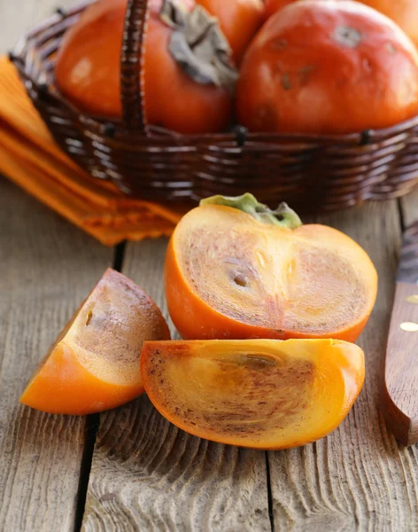 Fructe de persimmon întregi și tăiate pe o masă de lemn — Fotografie, imagine de stoc