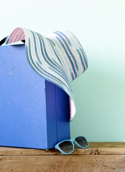 Old fashioned blue suitcase for travel and beach hat on a turquoise background — Stock Photo, Image