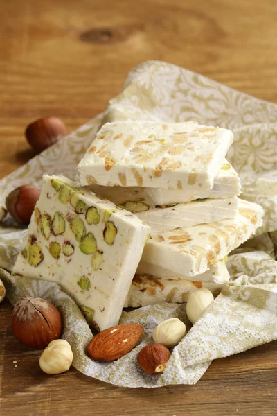 Vit nougat med olika nötter på ett träbord — Stockfoto