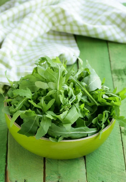 Schüssel mit grünem Salat mit Rucola auf Holztisch — Stockfoto