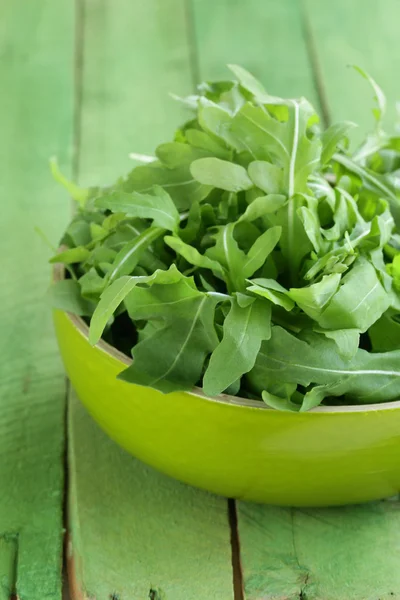 Skål med grönsallad med ruccola på träbord — Stockfoto
