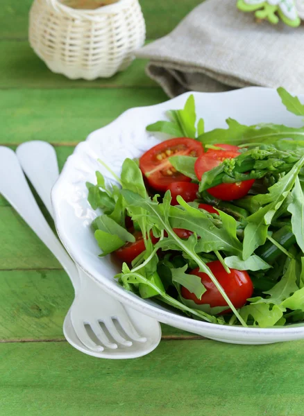 Salat mit Rucola und Tomaten serviert auf einem Holztisch — Stockfoto