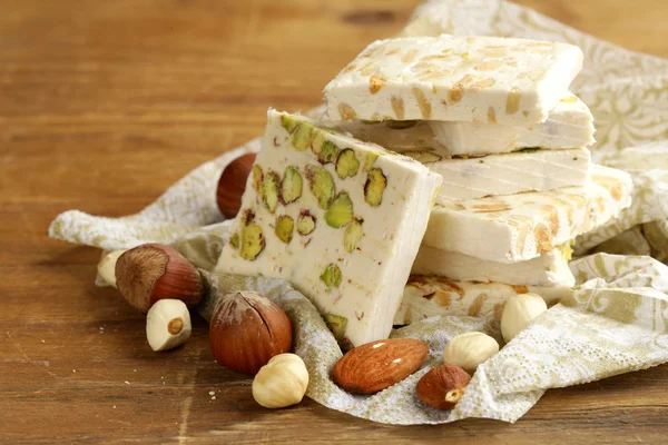White nougat with different nuts on a wooden table — Stock Photo, Image