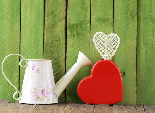 Bodegón para el Día de San Valentín: corazón de cerámica y regadera sobre un fondo de madera — Foto de Stock