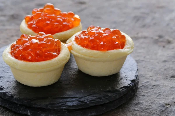 Gourmet tartlets with red caviar on a stone plate — Stock Photo, Image