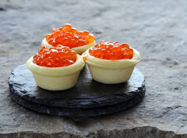 Gourmet tartlets with red caviar on a stone plate — Stock Photo, Image