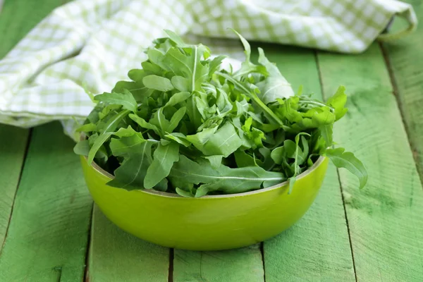 Bowl of green salad with arugula on wooden table — Stock Photo, Image