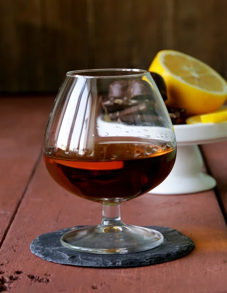 Vaso de brandy con chocolate sobre mesa de madera — Foto de Stock