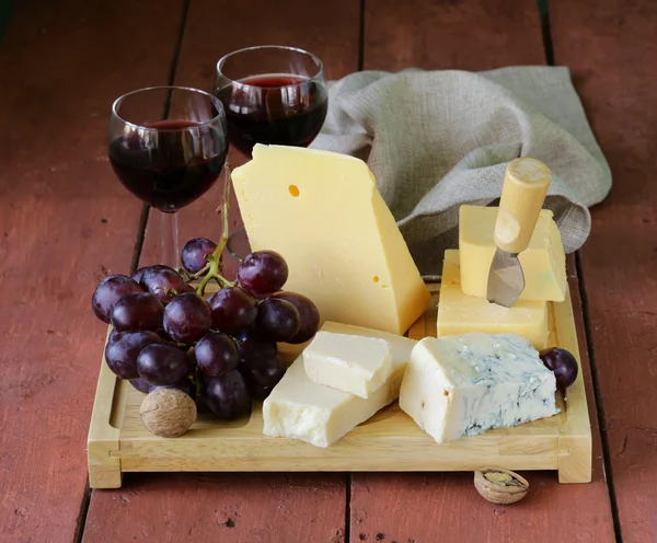 Cheese assortment served on a wooden board with grapes — Stock Photo, Image