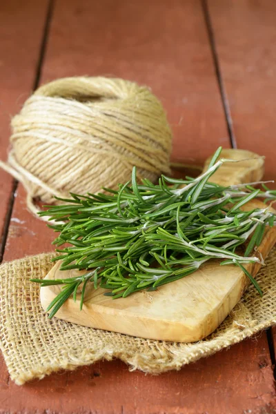 Rosemary verde fresco em uma tábua de corte de madeira — Fotografia de Stock