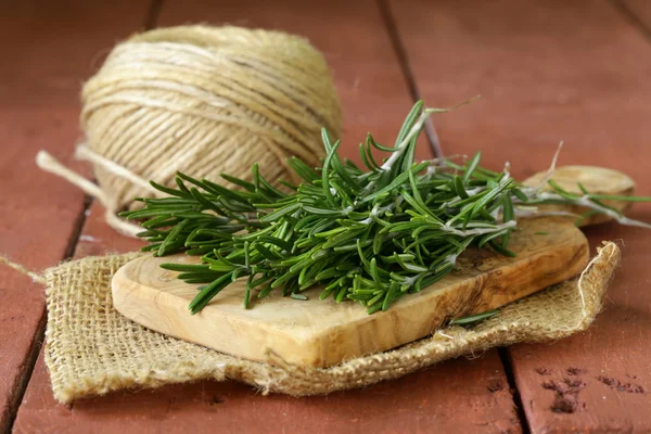 Rosemary verde fresco em uma tábua de corte de madeira — Fotografia de Stock