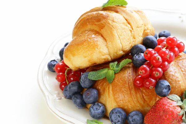 Свежий круассан с ягодами на завтрак на винтажной тарелке — стоковое фото