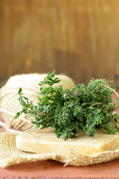 Bando de tomilho verde fresco em tábua de corte de madeira — Fotografia de Stock