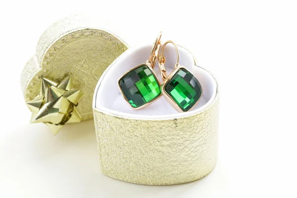 Gyllene örhängen med gröna stenar i en presentförpackning — Stockfoto