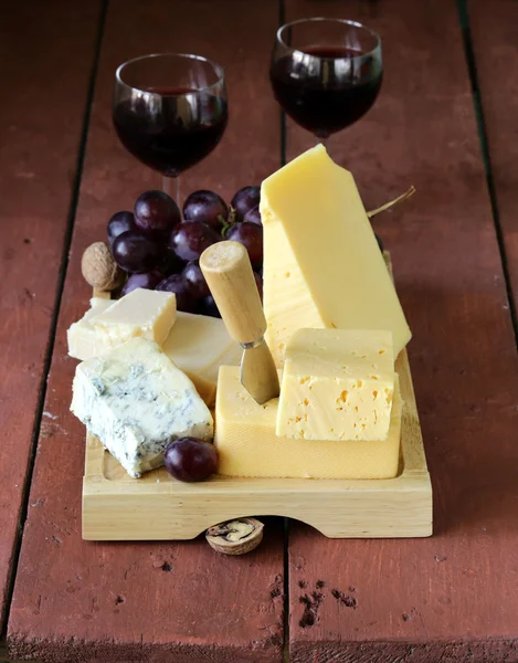 Cheese assortment served on a wooden board with grapes — Stock Photo, Image
