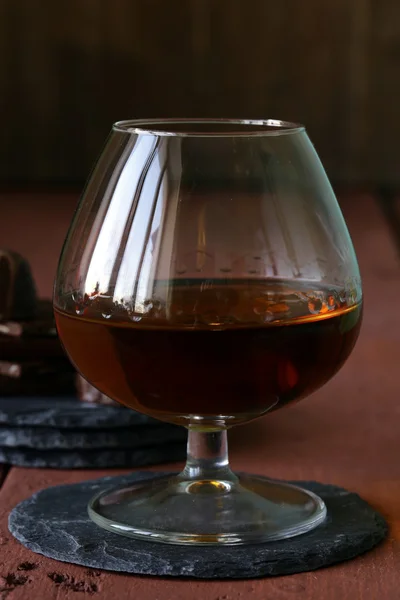 Glas Brandy mit Schokolade auf Holztisch — Stockfoto